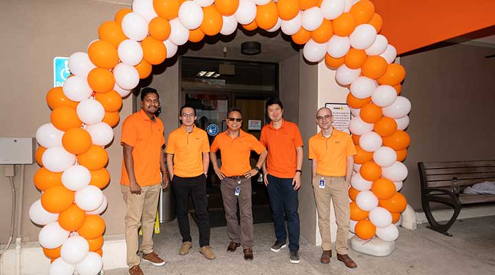 public storage employees stand together under orange and white balloon arch 
